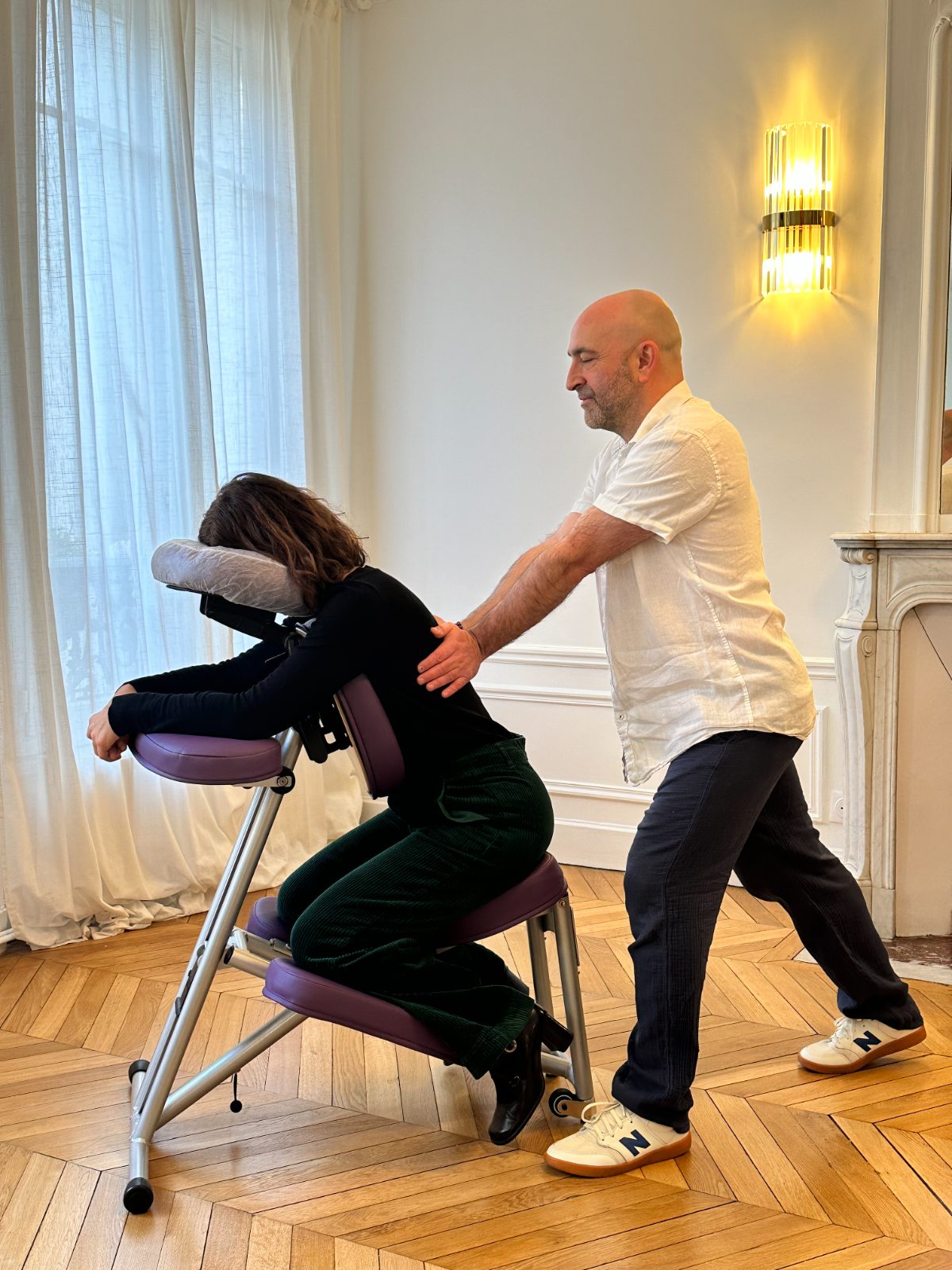 Renaud masse le dos d’une cliente installée sur la chaise ergonomique